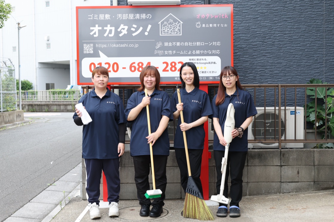 オカタシの看板の前に並ぶ女性スタッフ4名