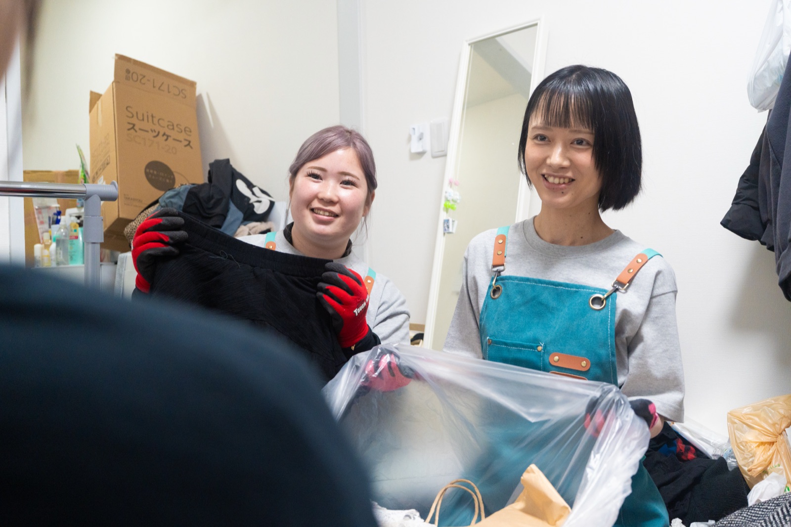 衣類を仕分けしながら片付け作業をする女性スタッフ2名